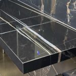 Maßgefertigte Waschtischplatte in Marmoroptik mit goldenen Marmoreierungen auf dunkler Fliese – exklusiv gefertigt vom Madak Meisterbetrieb in Wetzlar.