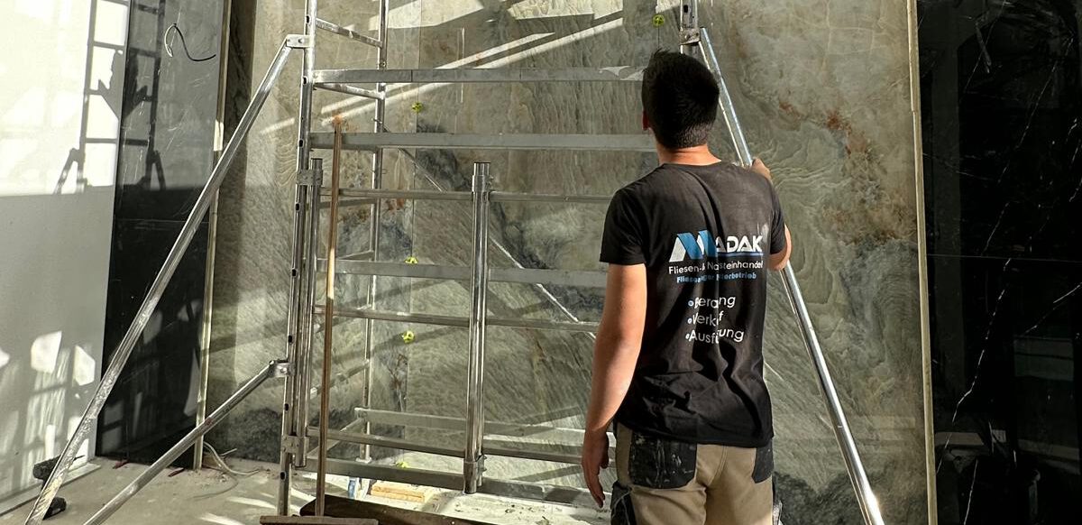 Madak Fliesenleger Team am beim verlegen. Wandfliesen Marmoroptik mit durchlaufender Maserung in 100 x 200 cm. Fliesenleger Gießen