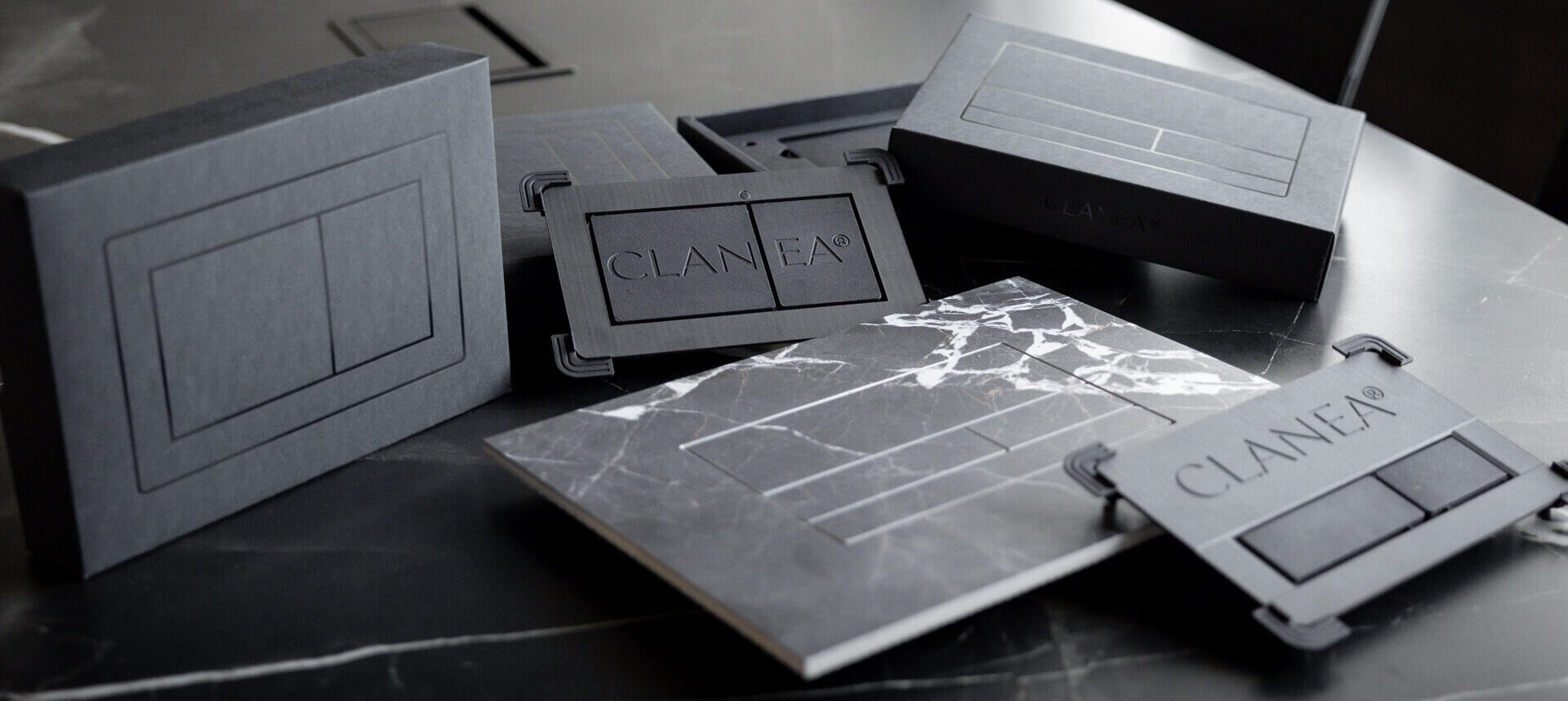 Befliesbares WC-Drückerplatten-Set „Clanea Purplate“ mit Montagegestell, verpackt und montiert auf Natursteinsockel mit Marmoroptik-Fliesen.