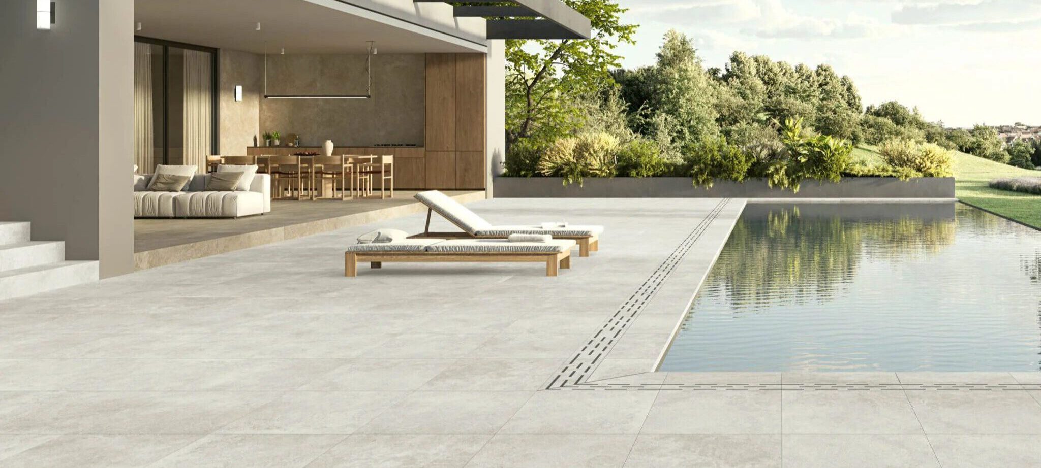 Moderne Poolumrandung mit trittsicheren Terrassenfliesen 120 × 120 cm in hellbeiger Spachteloptik, klare Oberfläche und überdachte Terrasse am Haus.