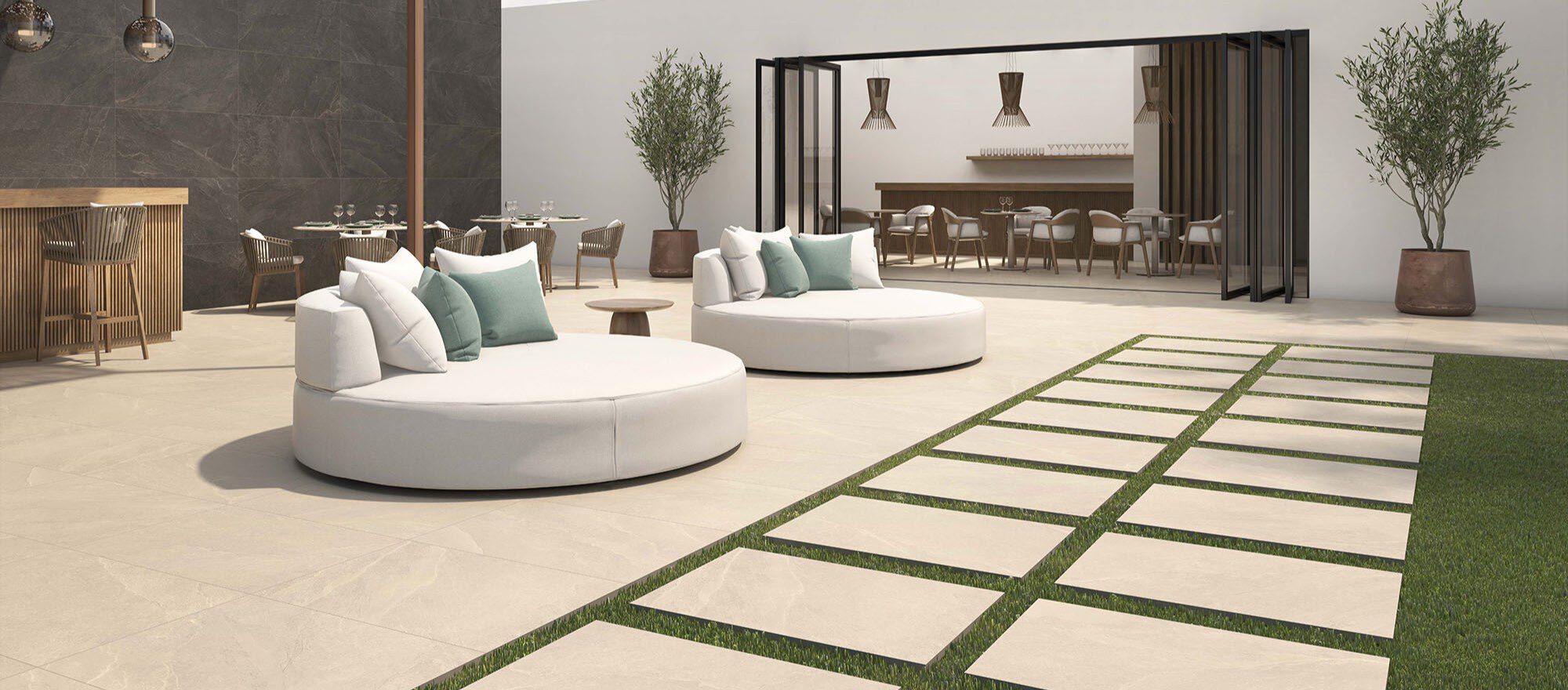 Große Terrasse mit hochbelastbaren 2 cm Feinsteinzeug-Terrassenfliesen, Sitzbereichen, Bar und Gartenweg auf der Wiese.